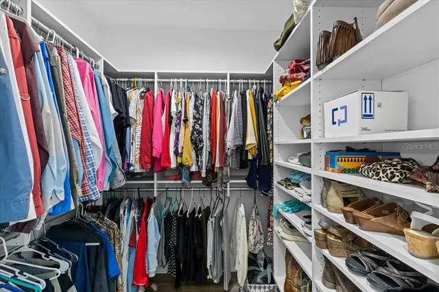 a view of walk in closet with clothes and shoes