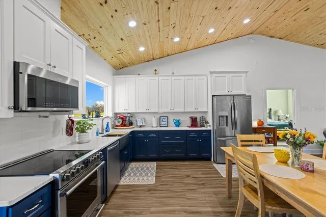 a kitchen with stainless steel appliances kitchen island granite countertop a refrigerator a stove top oven a sink dishwasher with wooden cabinets and floor