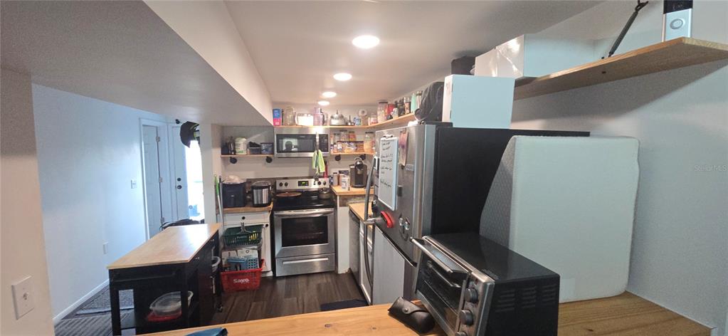 206 Lake Ida Road Frostproof, FL 33843 - Photo 19 of 46 a view of a kitchen with stainless steel appliances wooden floor and chairs