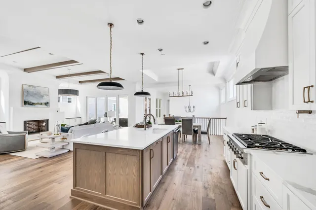 a large kitchen with stainless steel appliances a stove a sink dishwasher and a dining table with wooden floor