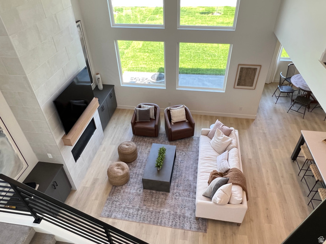 1951 2900 West Provo, UT 84601 - Photo 6 of 21 Spacious living area featuring a two-story tiled fireplace with a wood mantle, large windows providing natural light, light wood-finish flooring, and built-in cabinetry