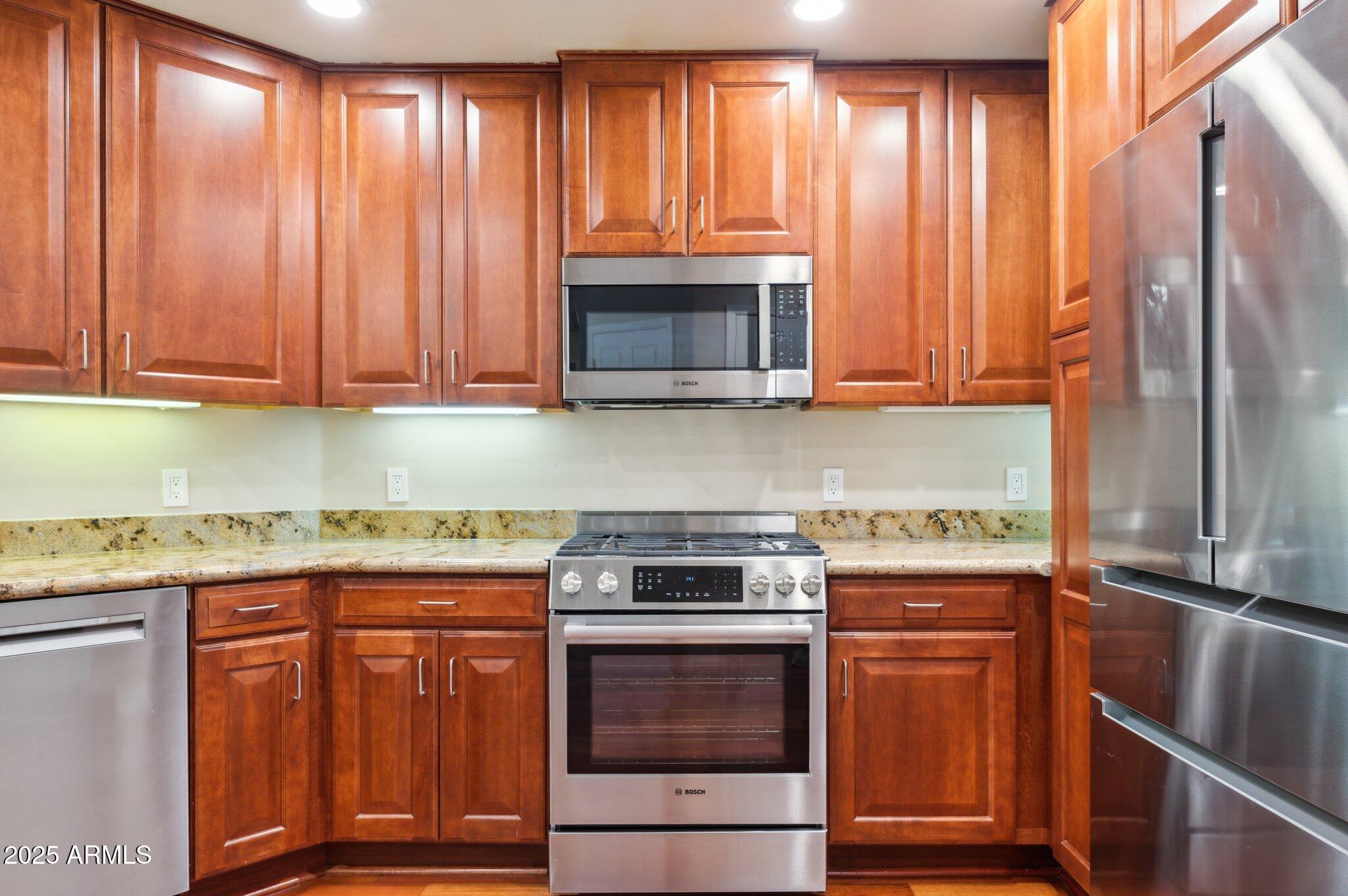 5450 East Deer Valley Drive, Unit 1214 Phoenix, AZ 85054 - Photo 1 of 35 a kitchen with granite countertop wooden cabinets and a stove top oven