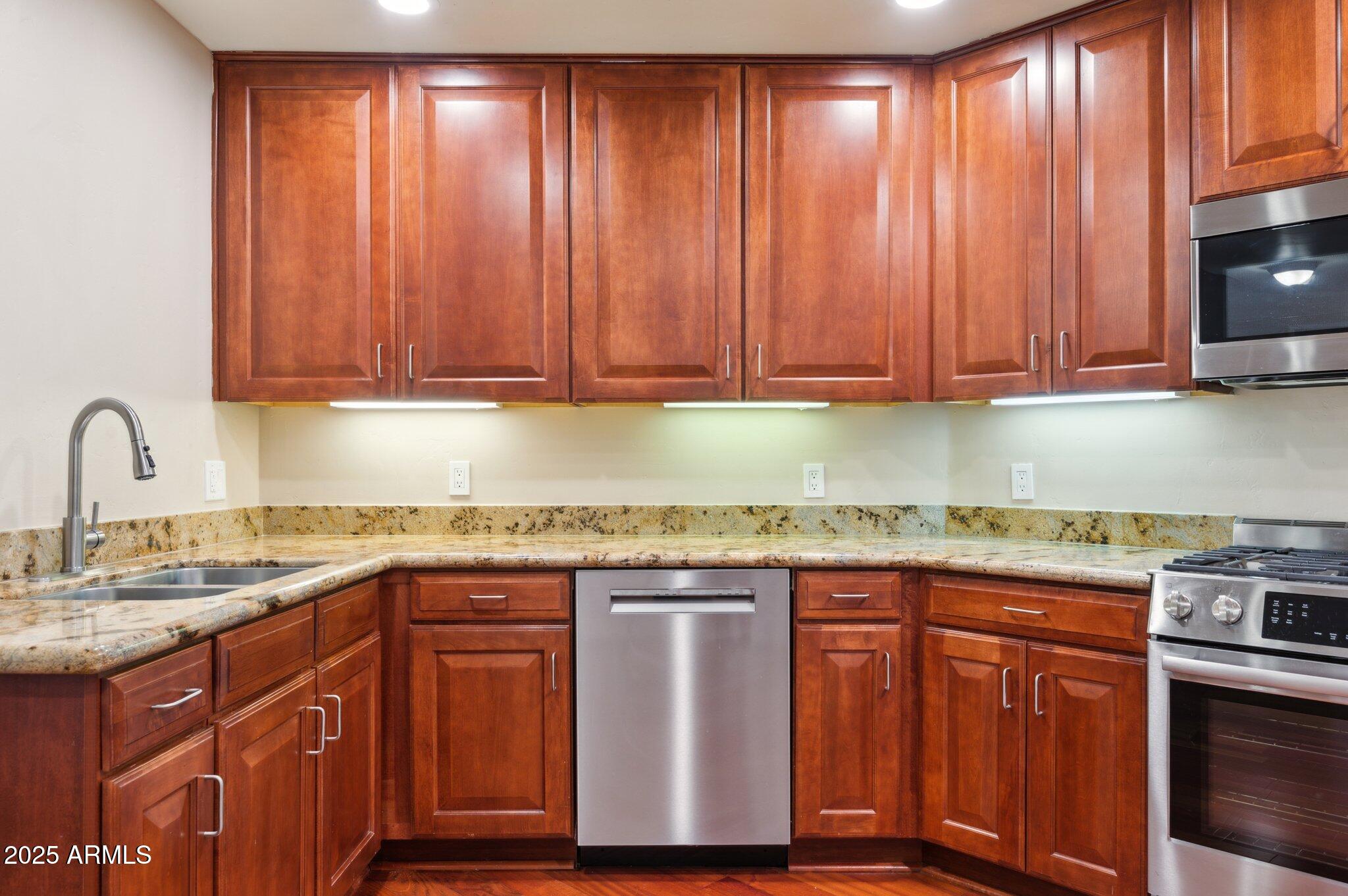 5450 East Deer Valley Drive, Unit 1214 Phoenix, AZ 85054 - Photo 35 of 35 a kitchen with granite countertop wooden cabinets a sink and dishwasher