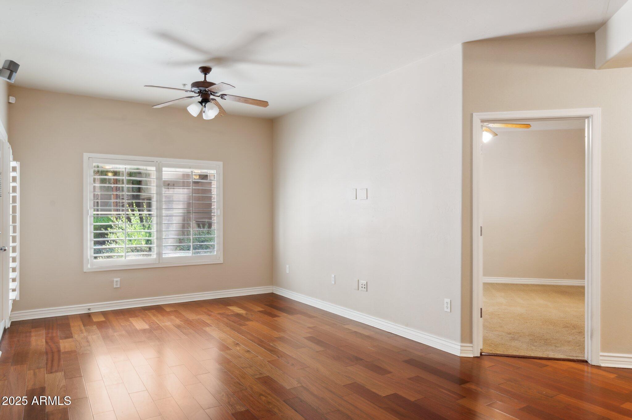 5450 East Deer Valley Drive, Unit 1214 Phoenix, AZ 85054 - Photo 7 of 35 an empty room with wooden floor chandelier fan and windows
