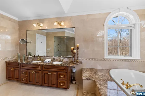 a bathroom with a granite countertop tub a double vanity sink and a mirror