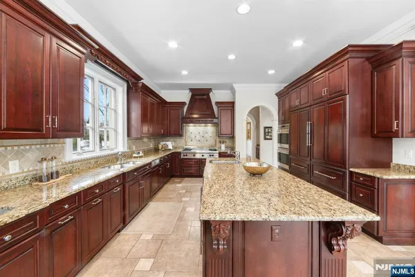 a large kitchen with kitchen island a large counter top stainless steel appliances and cabinets