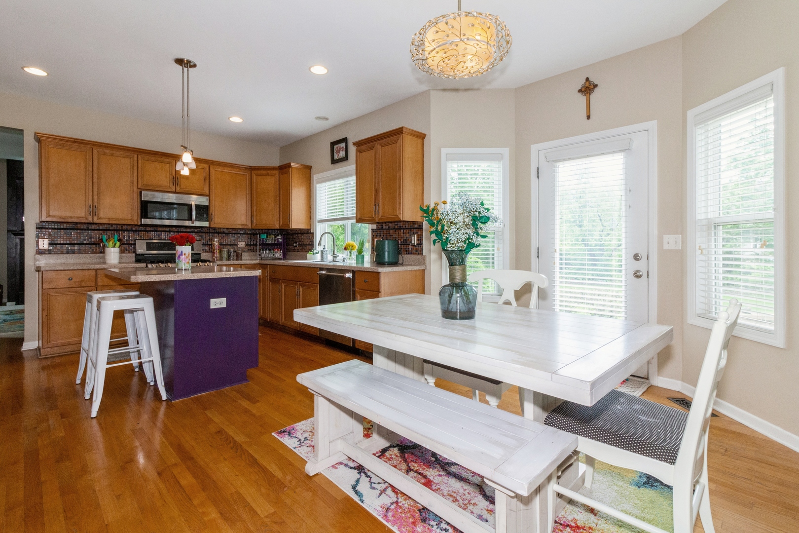 705 Queens Gate Circle Sugar Grove, IL 60554 - Photo 7 of 25 a kitchen with stainless steel appliances granite countertop a stove a refrigerator a sink dishwasher and a dining table with wooden floor