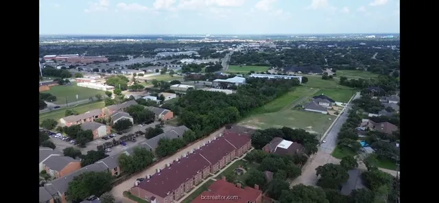 an aerial view of residential houses with outdoor space and trees