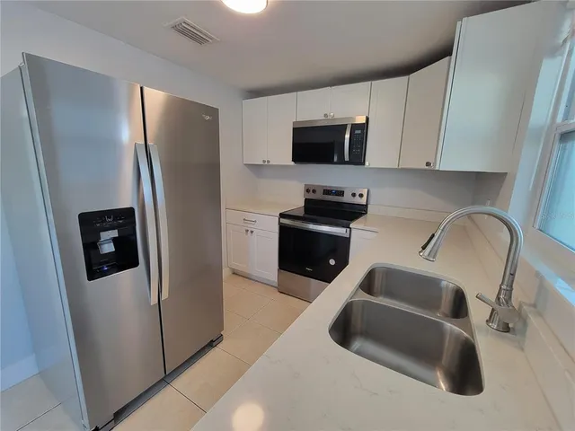 a kitchen with stainless steel appliances a refrigerator a sink a stove a microwave and cabinets