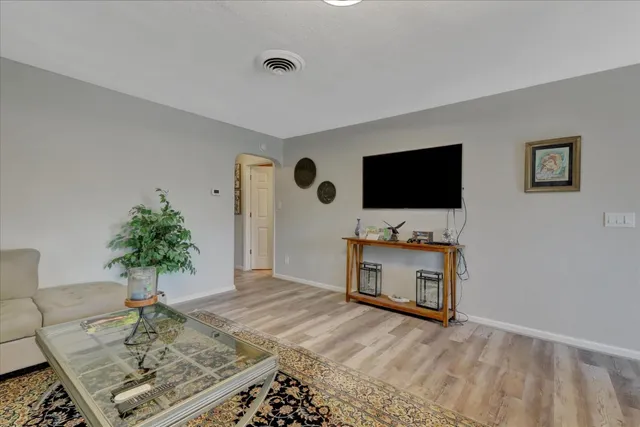 a large white kitchen with stainless steel appliances kitchen island granite countertop a table chairs in it and a flat screen tv