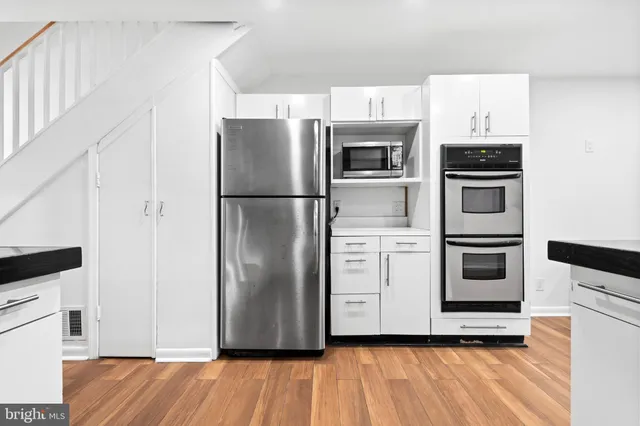 a kitchen with stainless steel appliances granite countertop a refrigerator a stove and a sink with wooden floor