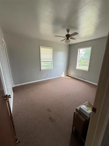 an empty room with windows and fan