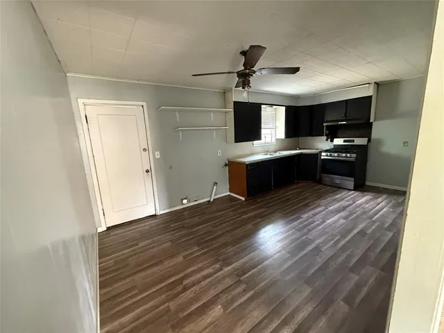 a large kitchen with kitchen island a sink dishwasher a refrigerator and a stove with wooden floor