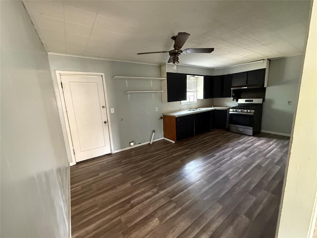 701 Perry Street Santa Anna, TX 76878 - Photo 5 of 13 a large kitchen with kitchen island a sink dishwasher a refrigerator and a stove with wooden floor