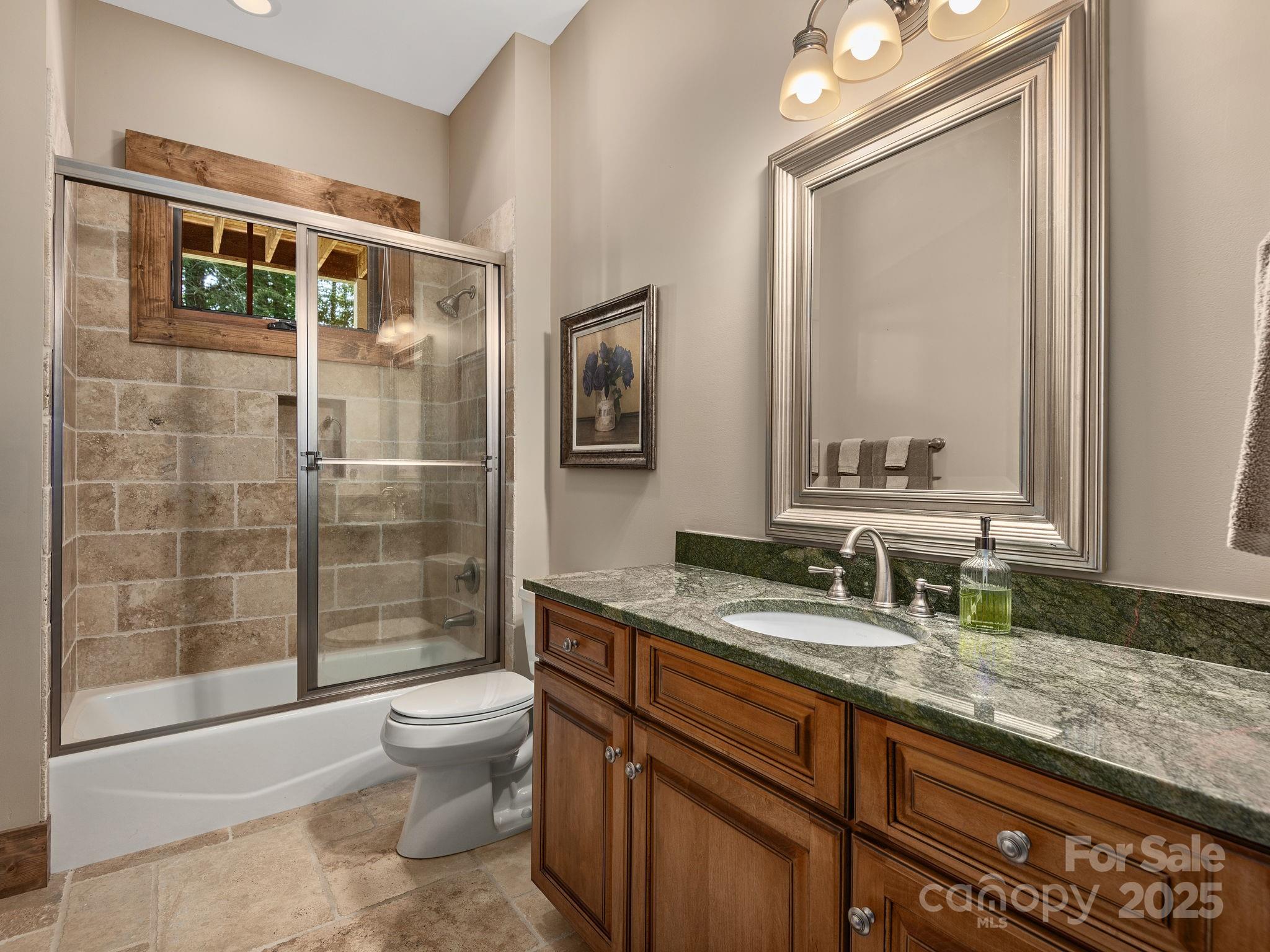 120 Mossy Rock Road Sapphire, NC 28774 - Photo 40 of 47 a bathroom with a granite countertop sink a toilet a mirror and shower