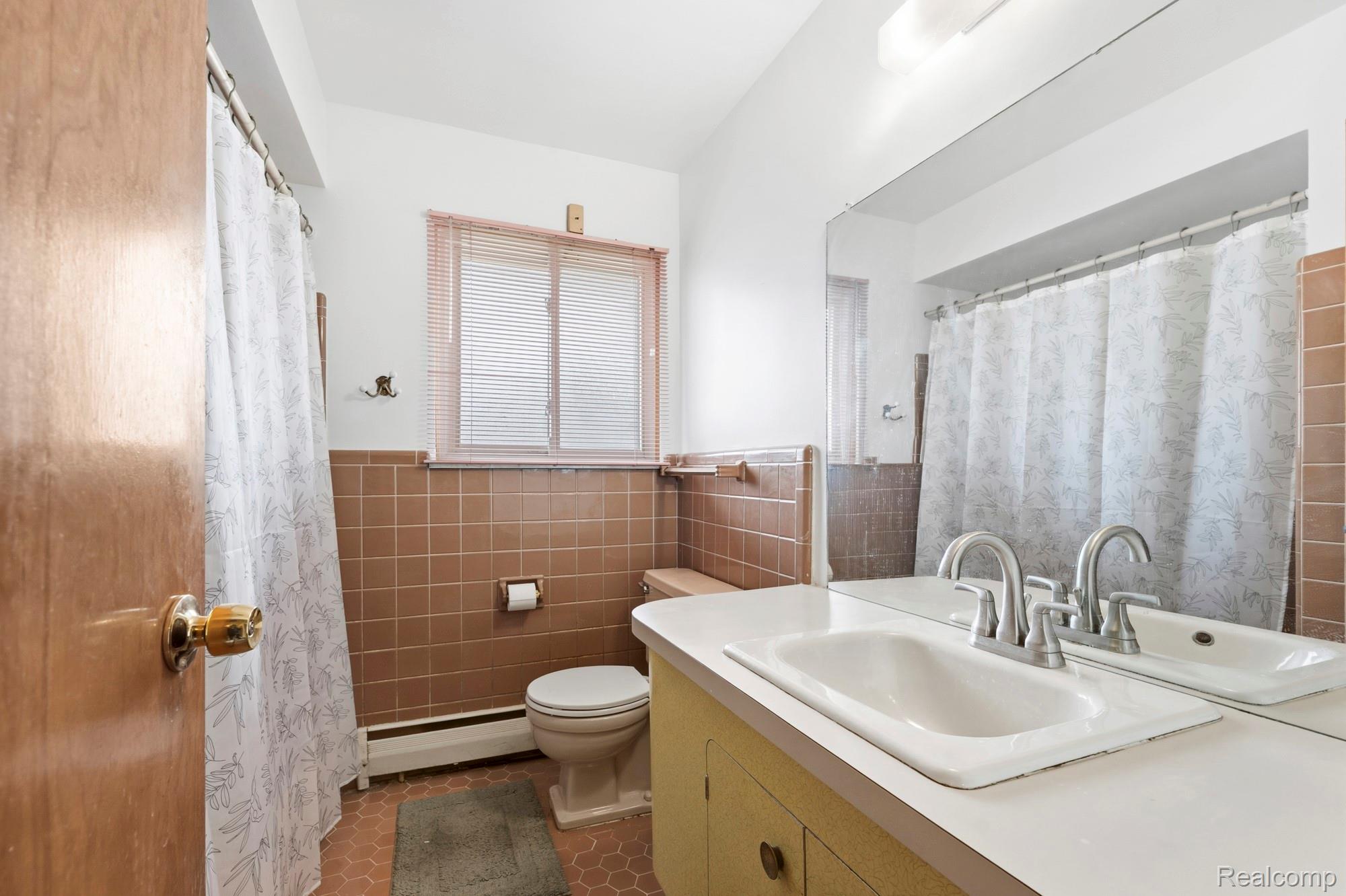 23410 Joy Road Redford, MI 48239 - Photo 13 of 25 Bathroom featuring a shower with shower curtain, vanity, tile walls, dark tile patterned floors, and a baseboard heating unit