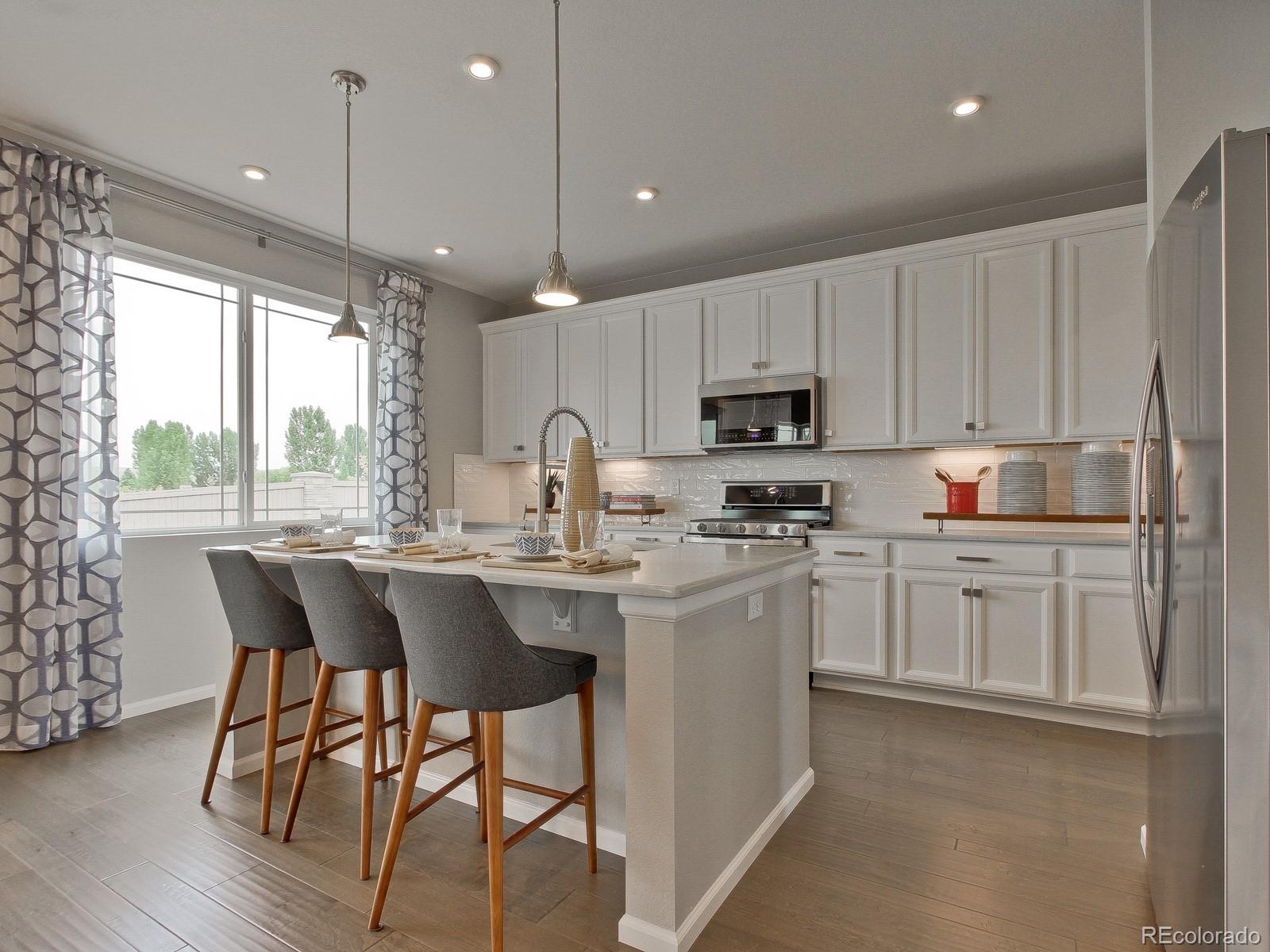 9196 Rifle Street Commerce City, CO 80022 - Photo 1 of 40 a kitchen with kitchen island granite countertop a sink a center island and cabinets