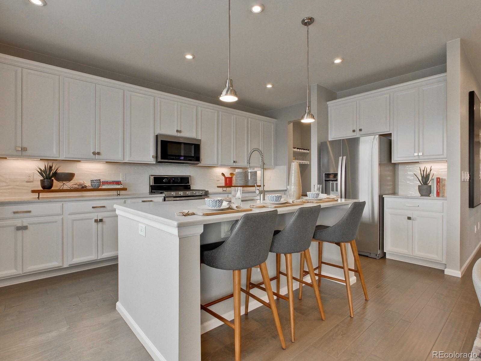 9196 Rifle Street Commerce City, CO 80022 - Photo 2 of 40 a kitchen with a dining table chairs refrigerator and microwave