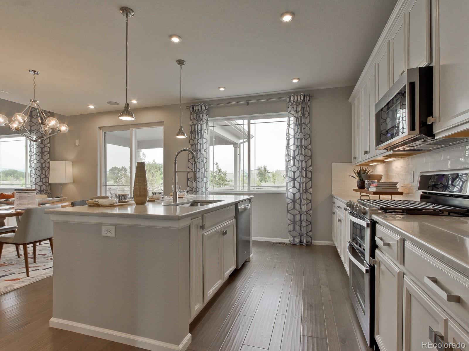 9196 Rifle Street Commerce City, CO 80022 - Photo 4 of 40 a kitchen with stainless steel appliances granite countertop a stove a sink a refrigerator and a microwave