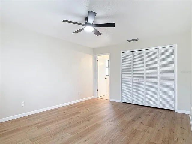 an empty room with wooden floor closet and windows