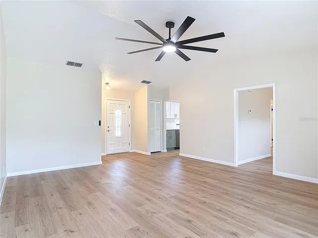 a view of a big room with wooden floor and windows