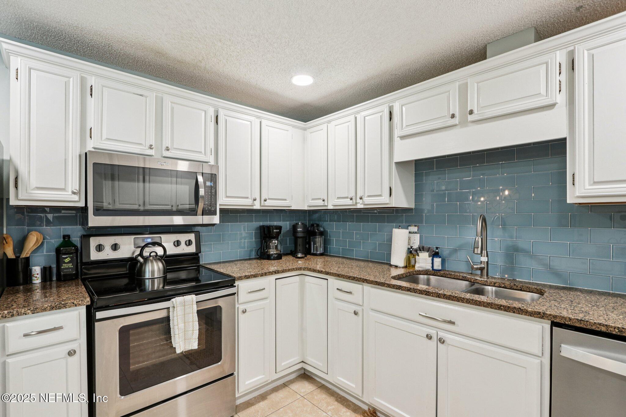 409 Seventeenth Street St. Augustine, FL 32084 - Photo 18 of 42 a kitchen with granite countertop white cabinets and white appliances