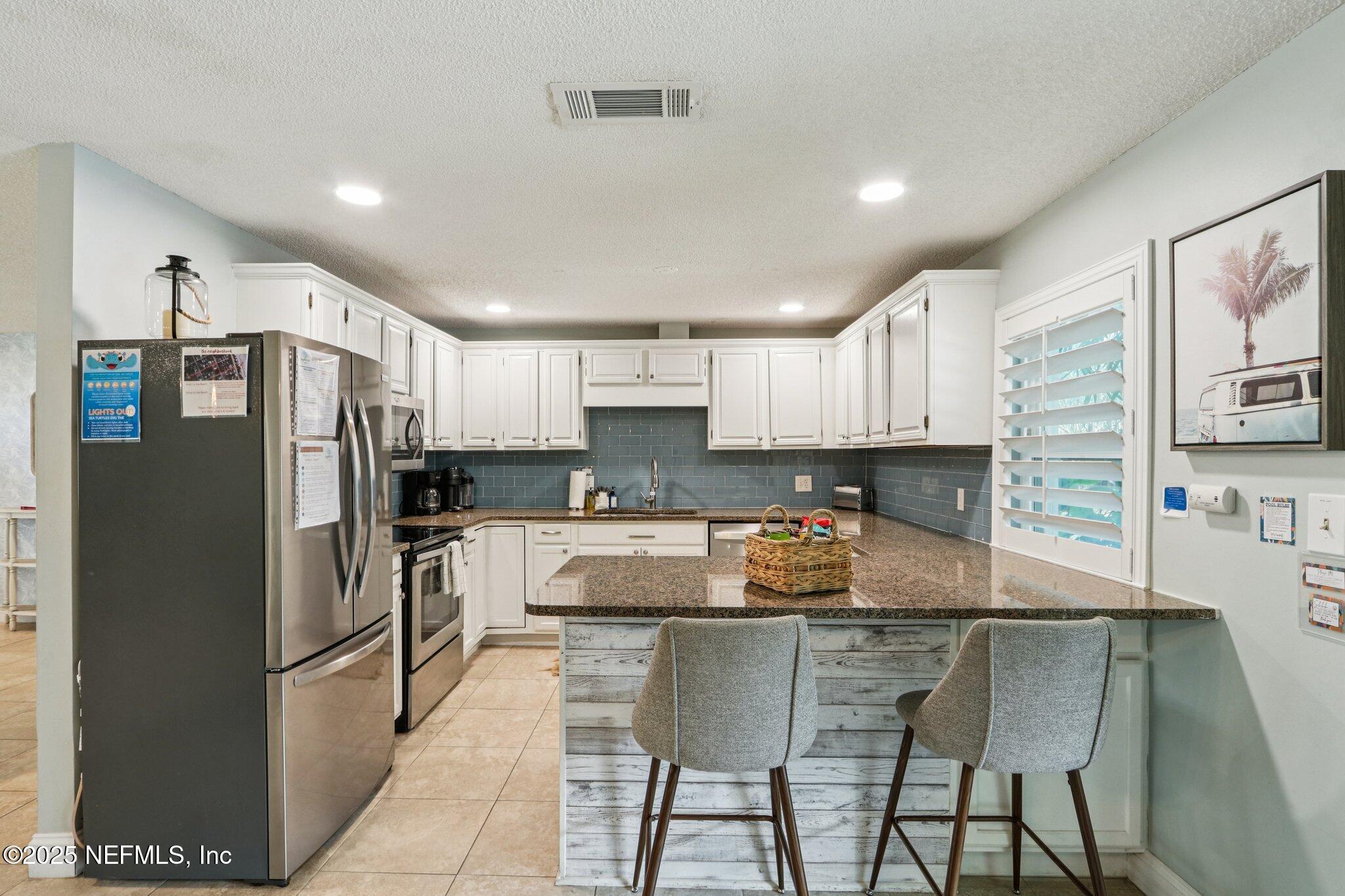 409 Seventeenth Street St. Augustine, FL 32084 - Photo 19 of 42 a kitchen with stainless steel appliances granite countertop a refrigerator and a stove top oven