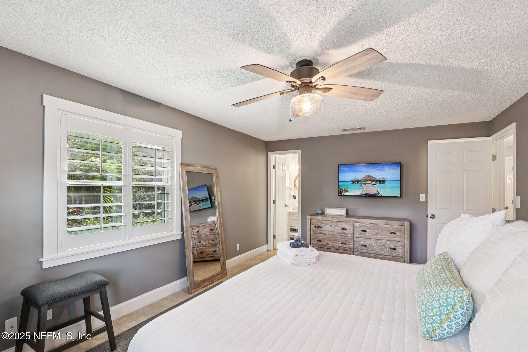 409 Seventeenth Street St. Augustine, FL 32084 - Photo 28 of 42 a bedroom with a bed a window and a flat screen tv