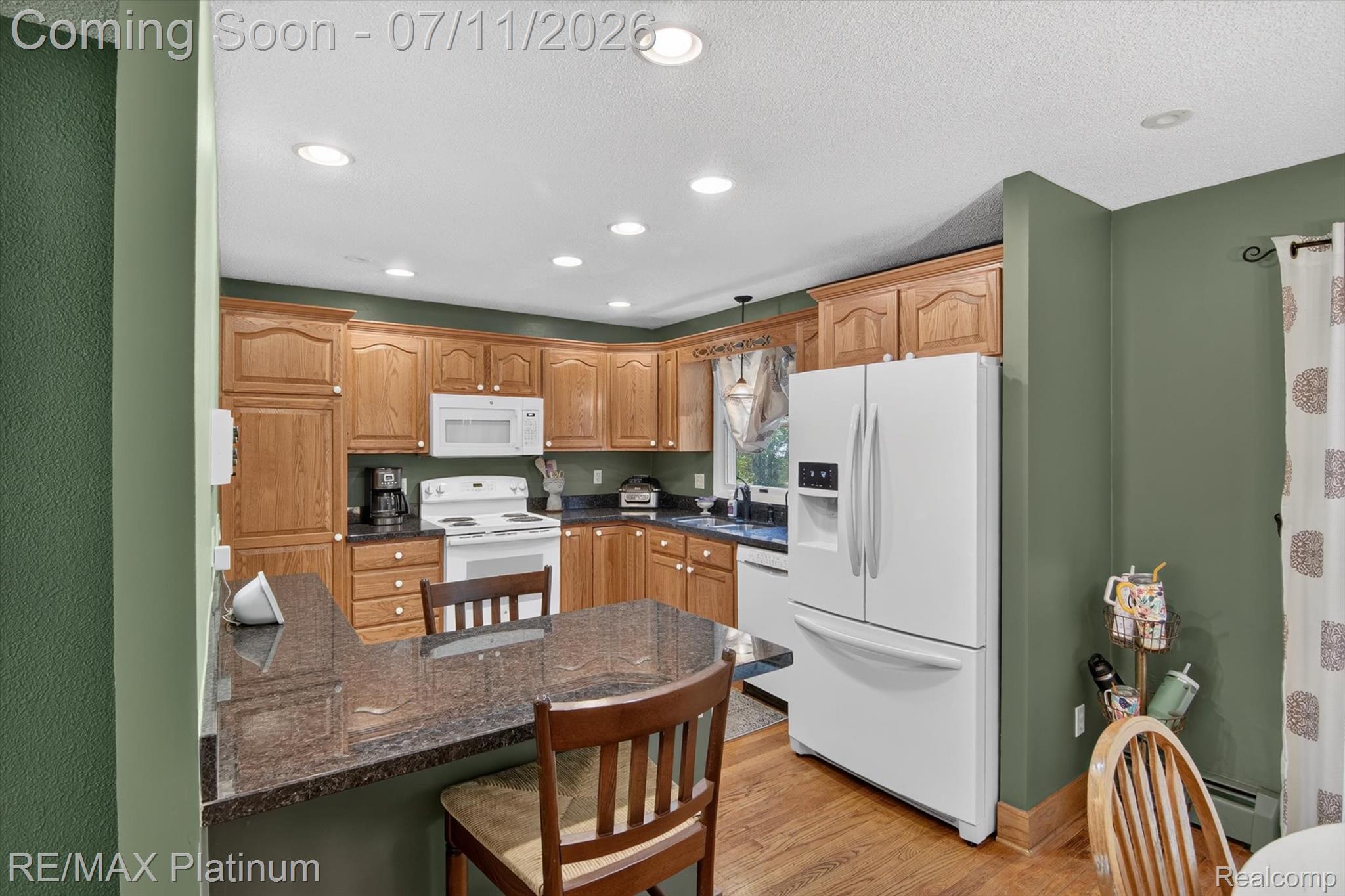 13365 North Territorial Road Gregory, MI 48137 - Photo 17 of 52 Kitchen featuring wood-finish cabinetry, white appliances, recessed lighting, and a breakfast bar with a stone-finish countertop