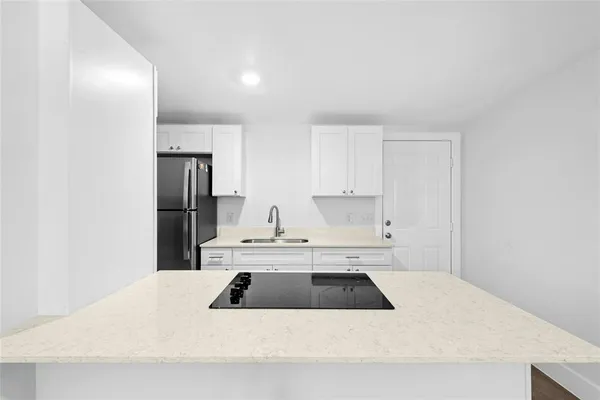a kitchen with a sink a refrigerator and white cabinets