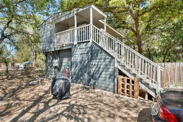 a view of a house with large trees and wooden fence