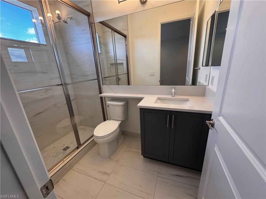 2864 Bloomfield Way Naples, FL 34112 - Photo 29 of 40 a bathroom with a sink a toilet a mirror and shower