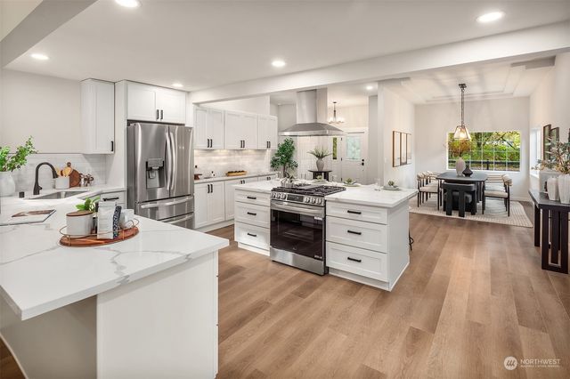 a kitchen with stainless steel appliances a sink dishwasher stove refrigerator and cabinets