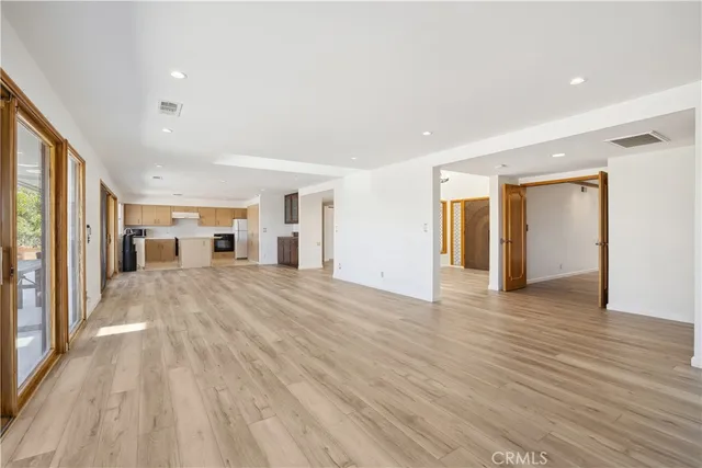 a view of a big room with wooden floor and windows