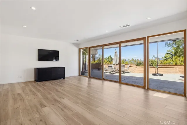 a view of an empty room with wooden floor and a floor to ceiling window