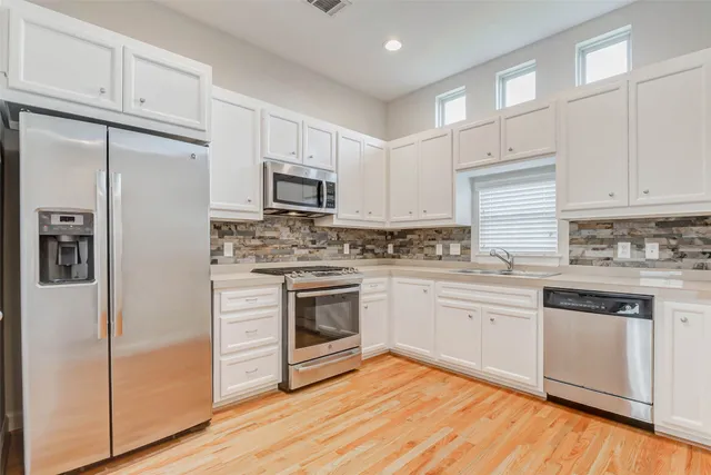 a kitchen with cabinets stainless steel appliances and wooden floor