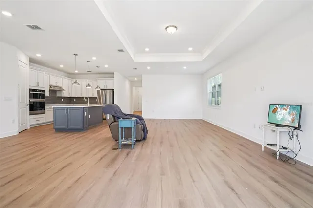 a large kitchen with kitchen island a stove a sink a refrigerator and a wooden floor