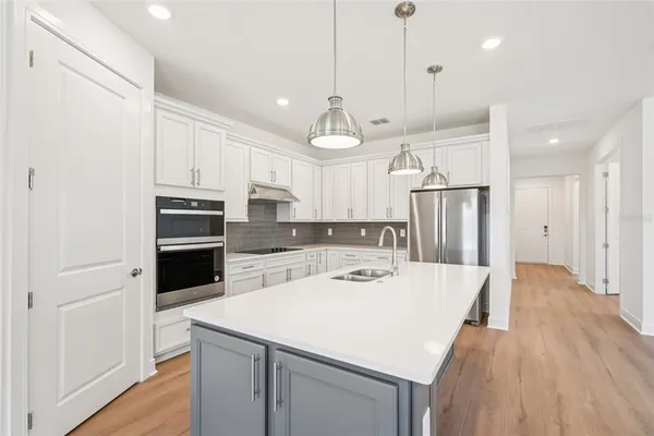 a kitchen with a white center island a refrigerator and cabinets