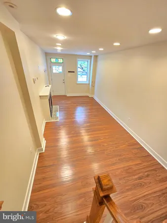 a view of an empty room with wooden floor and stairs