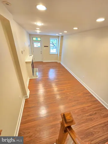 a view of an empty room with wooden floor and stairs