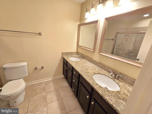 a bathroom with a granite countertop double vanity sink and mirror