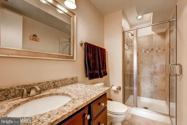 a bathroom with a granite countertop sink a toilet and shower
