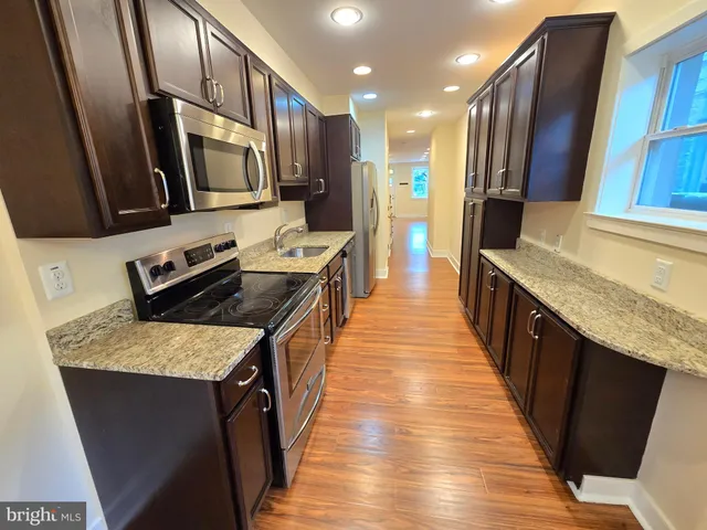 a kitchen with stainless steel appliances granite countertop wooden cabinets a sink dishwasher a stove and a refrigerator