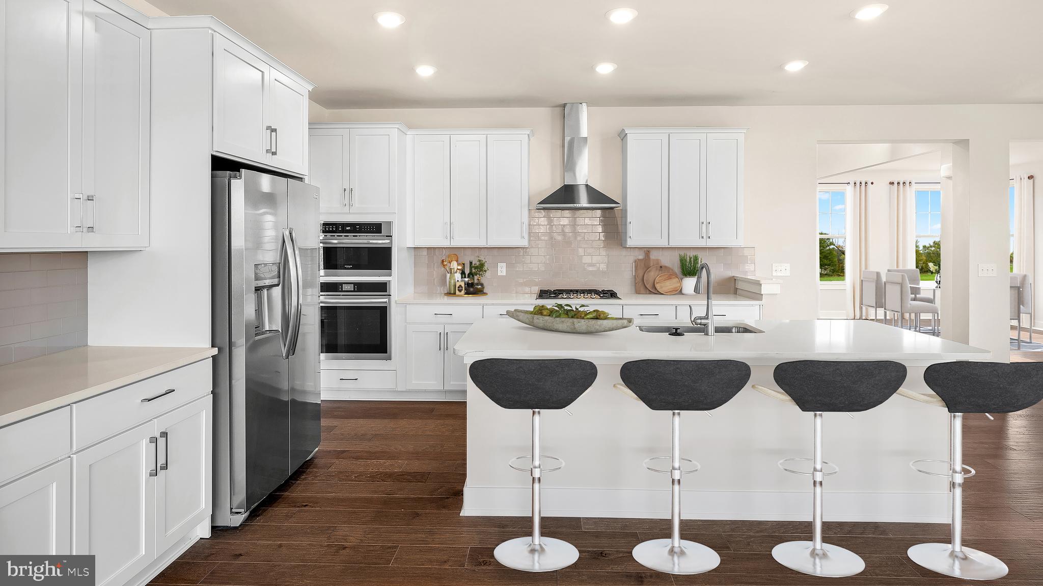 a kitchen with stainless steel appliances granite countertop a refrigerator a stove a sink counter tops and chairs with wooden floor