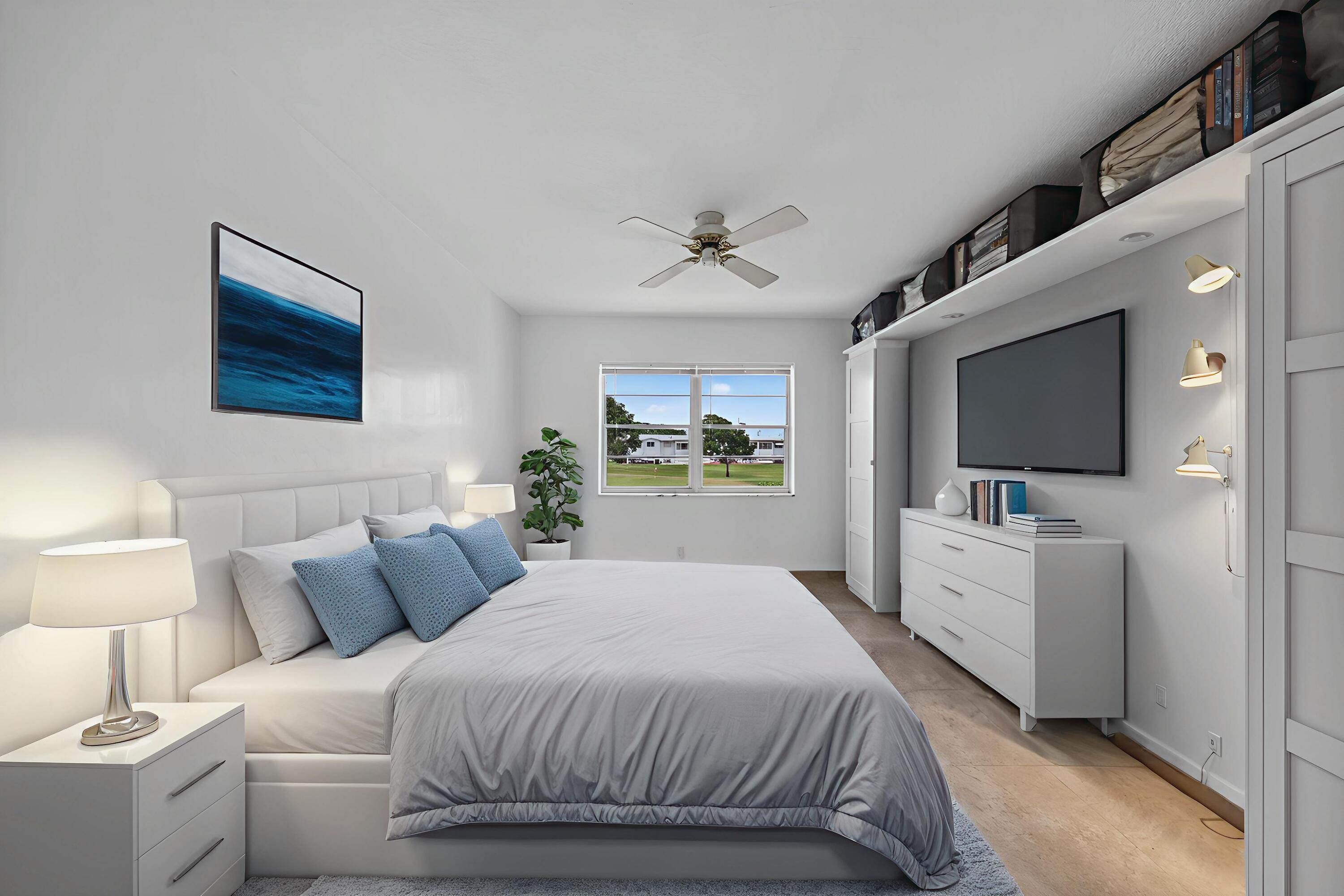 251 South Golf Boulevard, Unit 287 Pompano Beach, FL 33064 - Photo 23 of 63 a bedroom with a large bed a flat tv screen and a chandelier