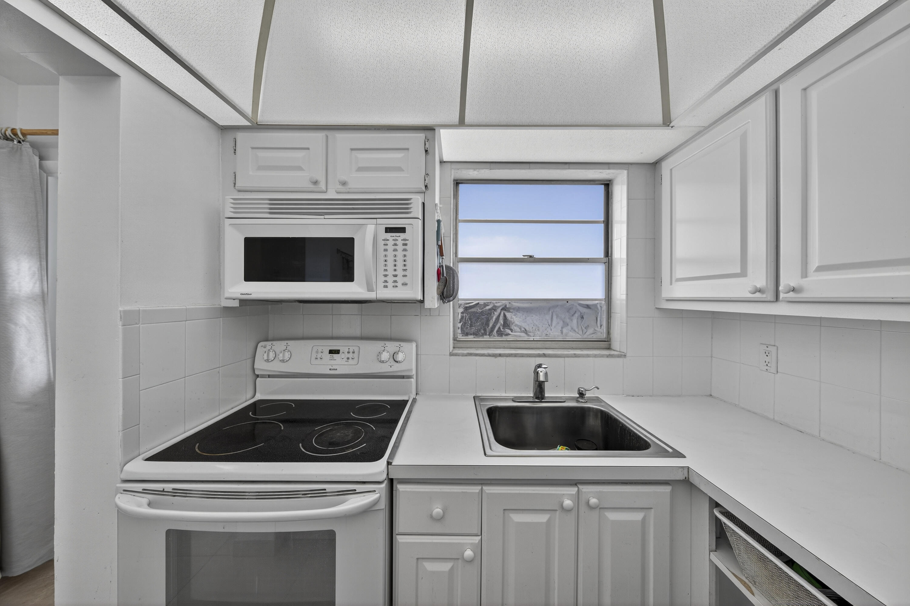 251 South Golf Boulevard, Unit 287 Pompano Beach, FL 33064 - Photo 4 of 63 a kitchen with white cabinets and appliances