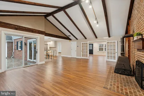 an empty room with wooden floor fire place and windows