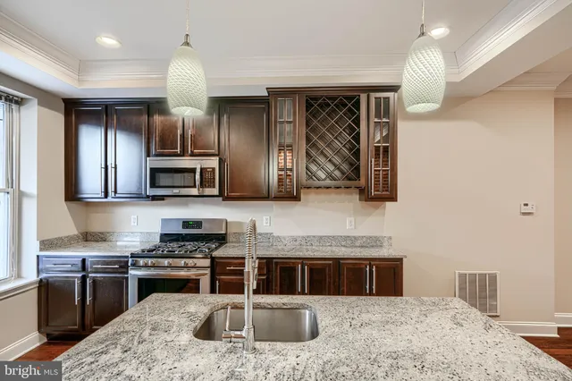 a kitchen with stainless steel appliances granite countertop a stove a sink and a microwave