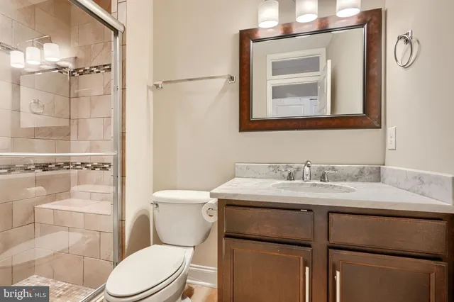 a bathroom with a toilet sink vanity and mirror