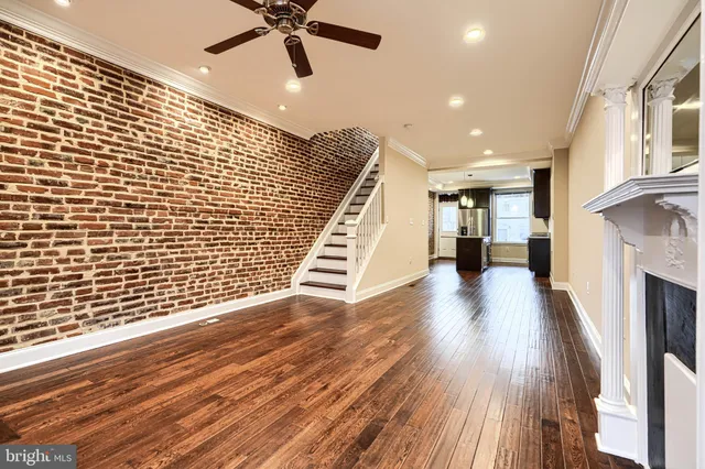 a view of an empty room with wooden floor and a ceiling fan